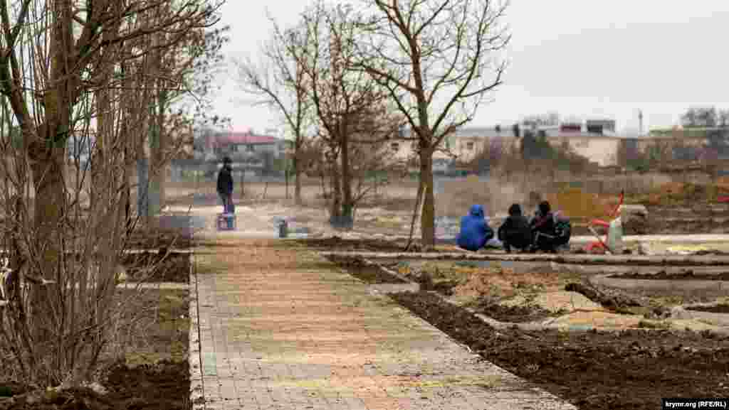 Робітники, задіяні в капремонті коштом уряду Москви території загального користування, разом із місцевими хлопчиками гріються біля багаття