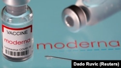 A vial labeled "Moderna coronavirus disease (COVID-19) vaccine" placed on displayed Moderna logo, March 24, 2021.
