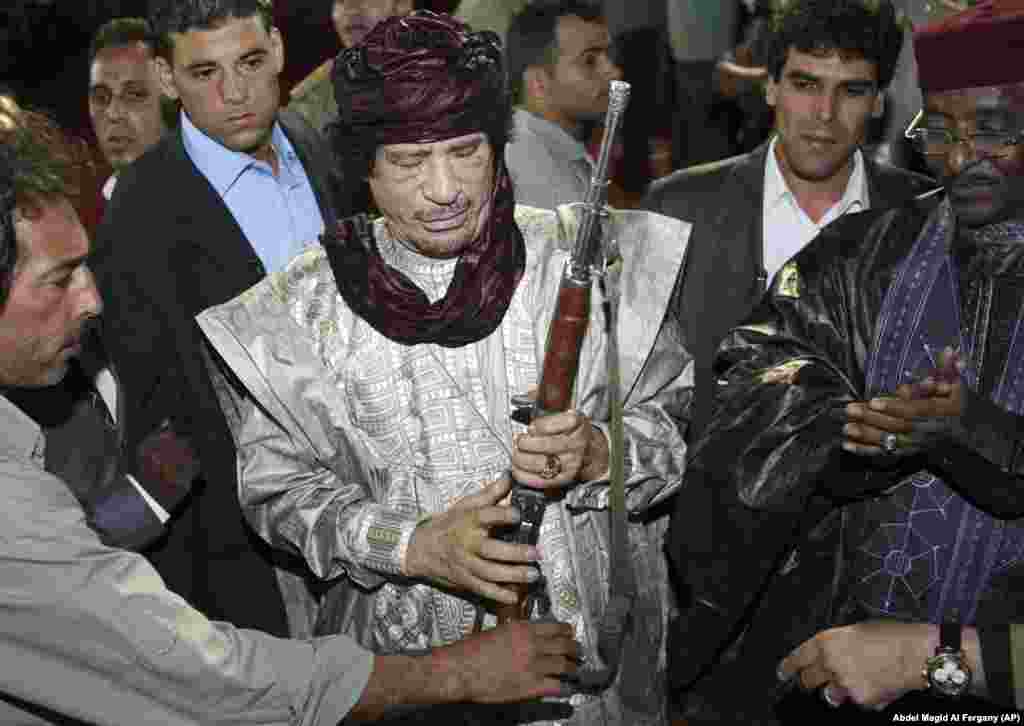 Ливияның бұрынғы басшысы Муаммар Каддафи 2009 жылдың қазан айында өзіне тайпа басшылары сыйға тартқан мылтықты ұстап тұр.