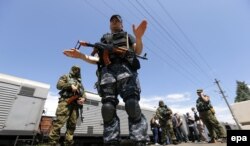 Separatiști înarmați gesticulează către presă in vreme ce păzesc un tren cu vagoane frigorifice ce conține trupuri ale pasagerilor avionului malaezian, duminică 20 iulie.