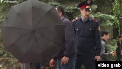 Наразылық кезінде қолшатырмен журналистердің жұмысына кедергі жасаған белгісіз адамдар және полиция қызметкері. 