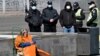 UKRAINE -- An elderly homeless woman asks for alms as police wearing face masks, amid concerns over the spread of the novel coronavirus COVID-19, patrol the streets of of Kyiv, April 5, 2020