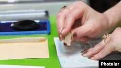 Armenia - An election official puts a stamp on a voter's passport in Yerevan, 6May2012.