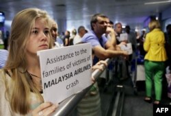 O femeie cu un panou pe care scrie "Sprijin pentru familiile victimelor avionului malaezian" așteptând un zbor din Amserdam pe aeroportul din Kiev, pe 22 iulie, 2014