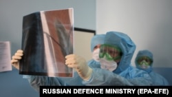 Науқастың рентген суретіне қарап тұрған медицина қызметкері. 