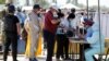 KAZAKHSTAN -- Local residents wearing protective masks walk through a checkpoint, set up to lock down the city to prevent the spread of the coronavirus disease (COVID-19), on the outskirts of Almaty, May 11, 2020