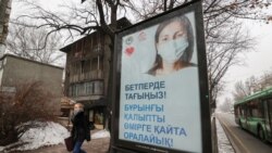 Прохожая возле баннера с призывом носить защитные маски. Алматы, 14 декабря 2020 года.