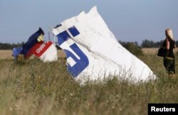 O femeie se fotografiază la locul prăbușirii avionului malaezian.