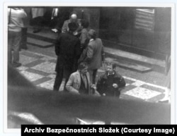 Вацлав Гавел (оң жақта) досы Иржи Динстбирмен әңгімелесіп тұр. Коммунистік билік екеуін ондаған жыл бойы қудалады. Гавел бірнеше жыл түрмеде отырды. Иржи Динстбирді 1968 жылы редакциядағы қызметінен қуғаннан кейін ол 20 жыл бойы вахтер болып жұмыс істеді. 1989 жылғы «барқыт революциясынан» кейін Иржи Динстбир сыртқы істер министрі болды, ал Вацлав Гавел Чехословакия президенті болып сайланды.