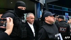 Владимир Плахотнюк, придружен от полиция, излиза от летището в Кишинев, 25 септември 2025 г.
