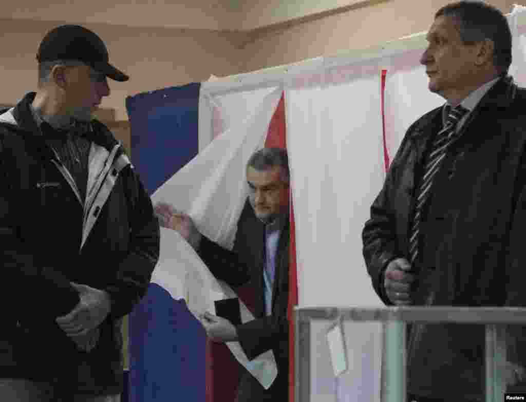Прэм'ер-міністар Крыму Сяргей Асёнаў (у цэнтры) выходзіць з кабінкі для галасаваньня ў Сімфэропалі.