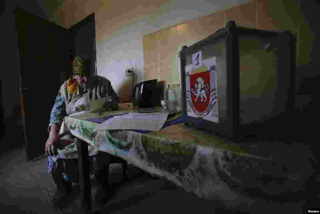 Жанчына разглядае бюлетэнь у сваім доме ў вёсцы Піянэрскае.
